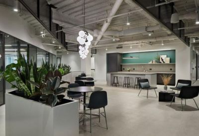 Bright breakout space with a kitchen island, cafe seating, and a cluster of globe pendant lights.