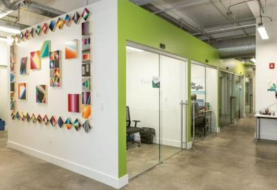 Modern communal lounge area featuring bright yellow armchairs and exposed ceiling ductwork.