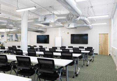 Bright hallway featuring glass-walled private offices and a vibrant green accent wall with abstract art.