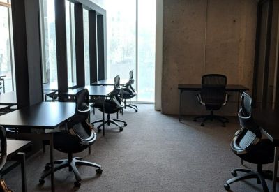 Internal office room with grey carpet, industrial ceilings, and black mesh chairs.