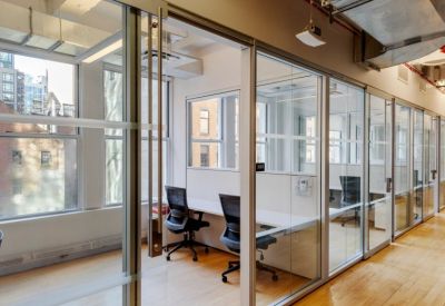 Private glass-enclosed office suites featuring minimalist white desks and ergonomic chairs.