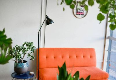 Lounge area with a bright orange sofa, floor lamp, and indoor plants.