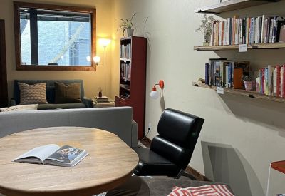 Cozy seating area with a wooden table, leather chair, and wall-mounted bookshelves.