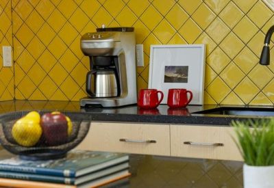 Close-up of a kitchen area with vibrant yellow tiled backsplash and coffee maker.