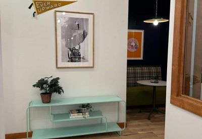 Hallway featuring a mint green console table, framed art, and a vintage 'Ever Upward' pennant.