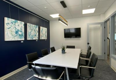 Conference room with a white table, navy feature wall, and abstract art.