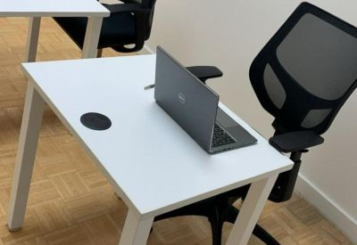 Individual workstation with a sleek white desk and ergonomic mesh chair.