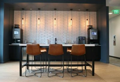 Communal kitchen area featuring a white subway tile backsplash and high-top leather barstools.