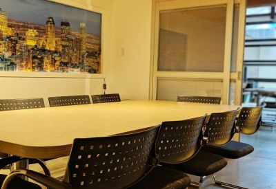 Professional meeting room with a long table, black mesh chairs, and city skyline artwork.