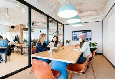 Meeting room with glass walls, a long wooden table, and blue and brown chairs.