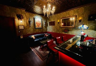 Vintage style lounge with red seating, a crystal chandelier, and patterned wallpaper.