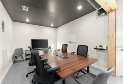 Private office suite featuring a wooden desk with unique black metal legs and blue curtains.