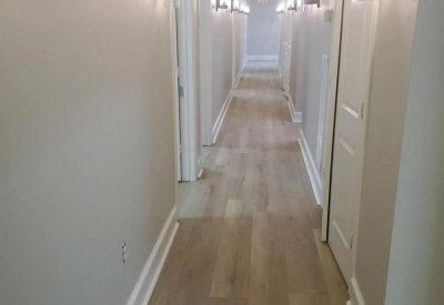 Long bright corridor at 506 Honea Egypt Road with wood-style flooring and wall sconces.
