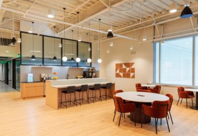 Bright dining area with a long breakfast bar, high stools, and orange velvet chairs.