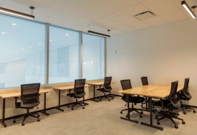 Minimalist workstation area with four desks and black ergonomic chairs by a window.