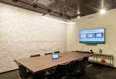 Modern boardroom with a long wood table, patterned feature wall, and large screen.