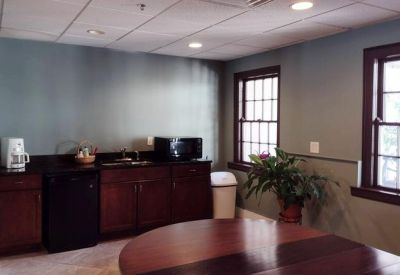 Breakroom kitchen featuring dark wood cabinetry and natural light from large windows.