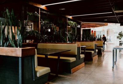 Sleek restaurant-style booths with dark wood tables and potted snake plants.
