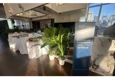 Event signage next to a buffet table and potted plants.