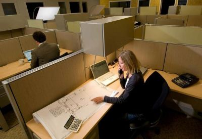Open-plan office workspace featuring individual cubicles and desks.