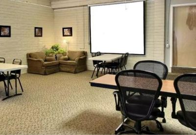 Meeting area featuring a projection screen, round tables, and mesh office chairs.