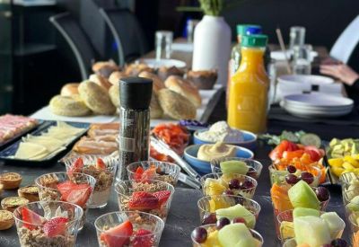 Catering spread with fruit cups, yogurt parfaits, and pastries on a black slate surface.