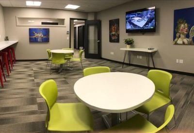 Communal break area with lime green chairs, round white tables, and wall art.