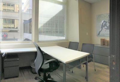 Internal office suite with two desks, grey ergonomic chairs, and large windows.