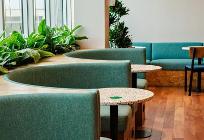 Semi-circular booths with green upholstery and plants