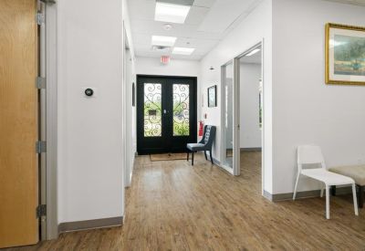 Bright reception area with wood floors, white walls, and a view through to the glass front doors.