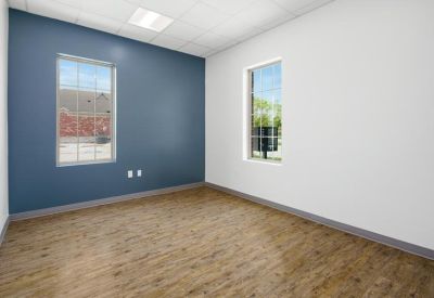 Empty private office with a blue accent wall and large windows overlooking the grounds.