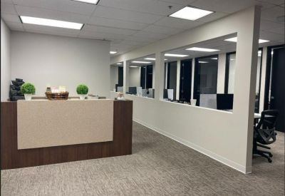 Professional reception area with a dark wood desk and potted greenery.