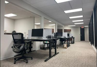 Bright open-plan workspace with height-adjustable desks and ergonomic chairs.
