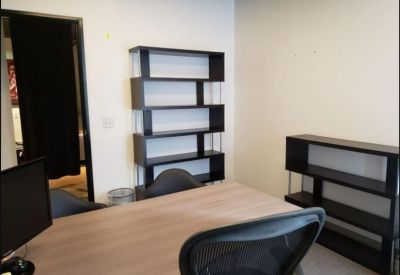 Meeting area with a large wooden table, mesh chairs, and minimalist shelving.