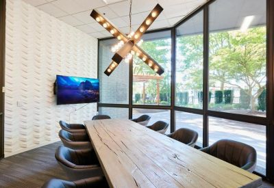 Meeting room with a reclaimed wood table, textured feature wall, and a large X-shaped Edison bulb chandelier.