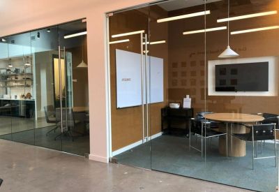 Contemporary glass-walled meeting rooms with round tables and sleek black chairs.