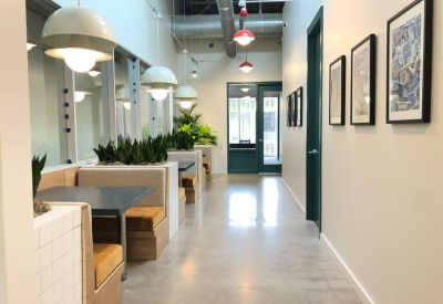 Modern corridor with built-in booth seating, greenery, and framed art on the walls.