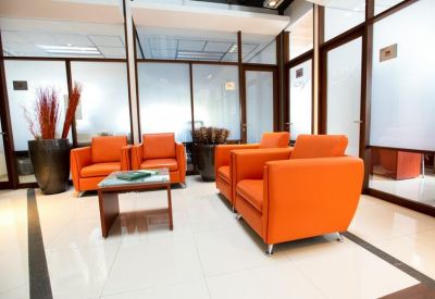 Reception area with vibrant orange armchairs and frosted glass partitions.