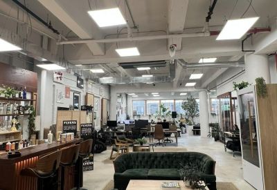 Bright lounge area featuring green velvet sofas and a bar with high stools.