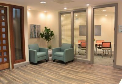 Waiting area with blue armchairs and a view into a glass-walled meeting room.