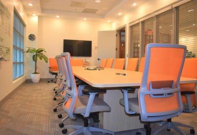 Large conference room with a light wood table and orange mesh office chairs.
