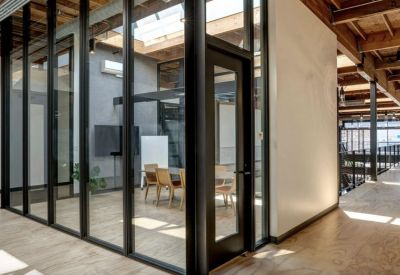 Modern glass-walled meeting room with wooden table and chairs.