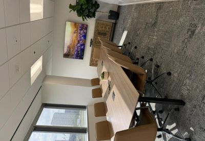 Bright conference room with a large wooden table, tan chairs, and a window overlooking the city.