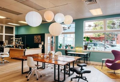 Large wooden communal table under globe pendant lights in a sunlit room.