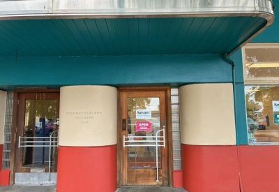 Main entrance door under a teal awning with red and cream architectural details.