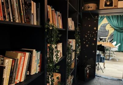 Library area with black shelving filled with books and trailing indoor plants.