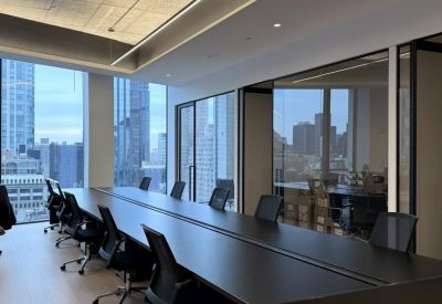 Modern open-plan workspace with sleek black desks and light wood flooring.