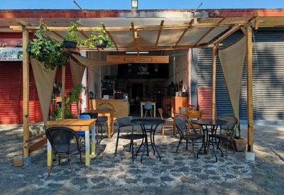 Covered outdoor patio with café tables and chairs under a wooden pergola.