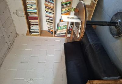Cozy reading corner with a black leather sofa and tall wooden bookshelves.