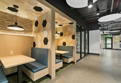 Bright workspace with upholstered booths and a view toward the main entrance.
